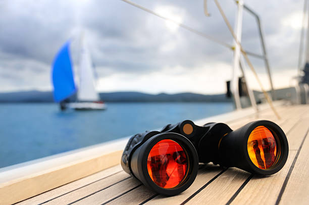 Close up on binocular on deck of yacht with another yacht on horizon in natural blur. Picture taken in Boka Kotorska bay
