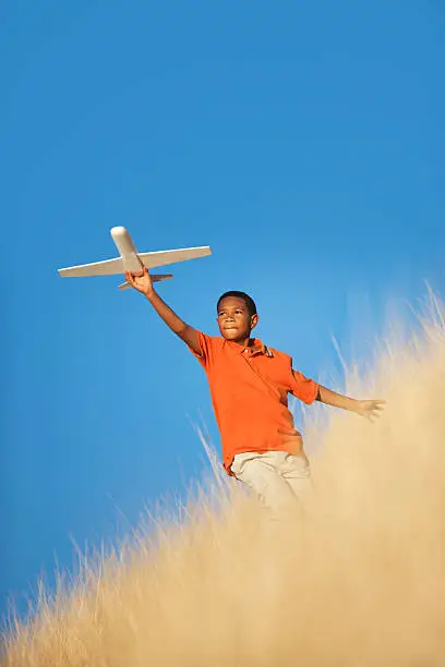Photo of Young Boy Playing with Toy Glider Airplane in Field