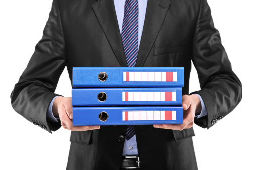 A close up of a businessman holding three blue folders isolated on white background