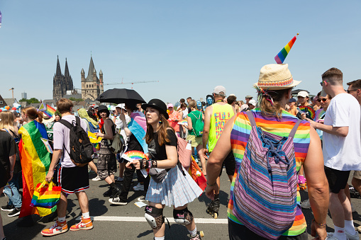 Cologne, Germany - July 9,2023: The christopher street day parade in Cologne has just started on the Deutzer Brückeat a very hot summer day, Participants oft he parade wearing costumes ith rainbos as symbol of the lgbtqia movement, Cologne cathedral can be seen in the background