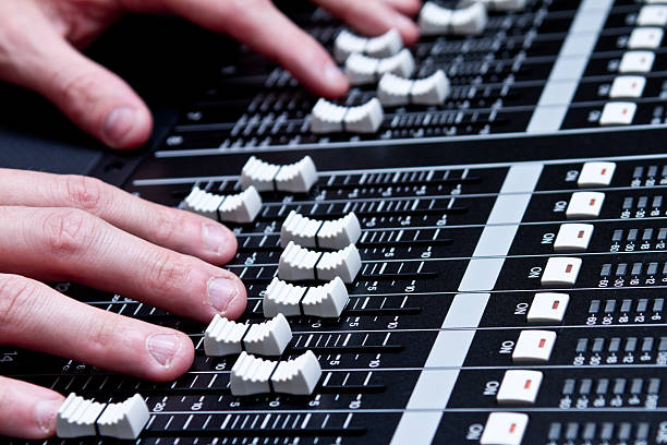 Dramatically lit detail of a new digital sound board, referred also to a console or desk.  This piece of high tech equipment is used in professional applications for live sound reinforcement and recording of music and spoken word.