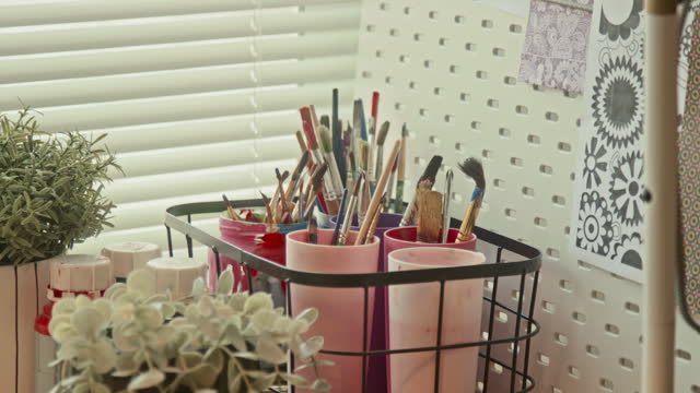 Paintbrushes in Vessels on Table in Loft Studio