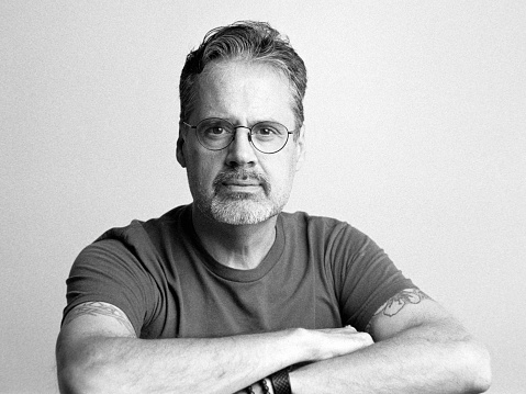 A studio portrait of a middle aged caucasian man. Photographed on 35mm black and white film and digitally scanned.