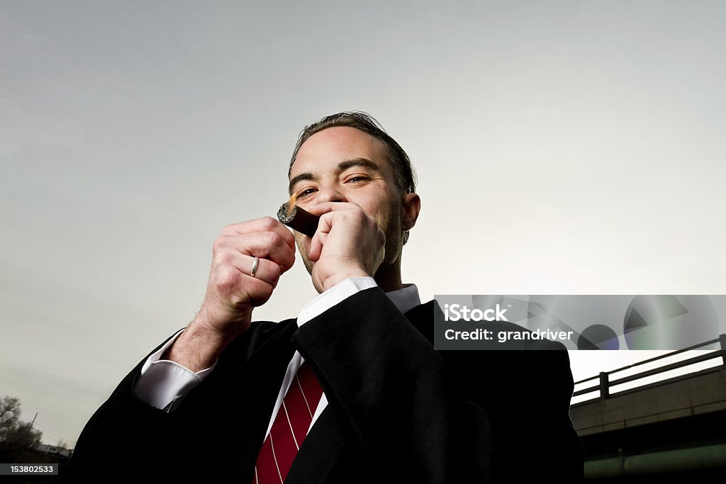 Minacciosa uomo sotto il ponte del sigaro di illuminazione - Foto stock royalty-free di Abbigliamento elegante