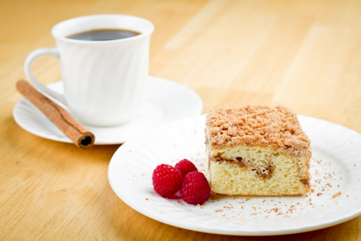 Coffee Cake with Cinnamon and Raspberries arranged on a white plate with ground cinnamon on the plate