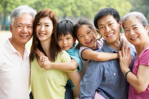 Portrait Of Multi-Generation Chinese Family Relaxing In Park Together Smiling To Camera