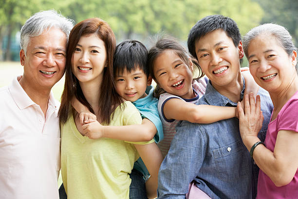 Portrait Of Multi-Generation Chinese Family Relaxing In Park Tog Portrait Of Multi-Generation Chinese Family Relaxing In Park Together Smiling To Camera china chinese ethnicity smiling grandparent stock pictures, royalty-free photos & images