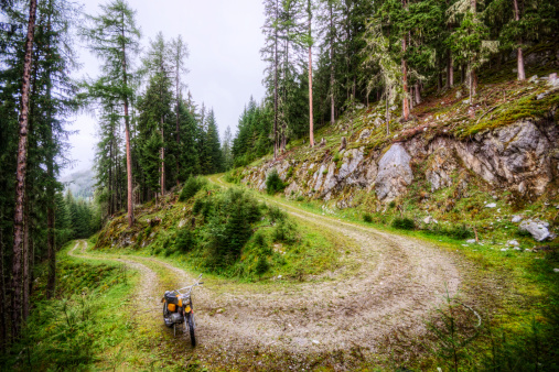 Dirt bike parked on road winding up a mountain in the European Alps.