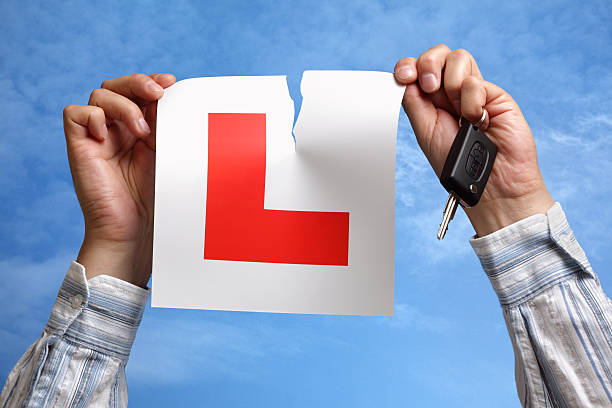 Tearing up L plate after passing driving test Tearing L plate against a sky holding a car key after passing driving test driving test photos stock pictures, royalty-free photos & images