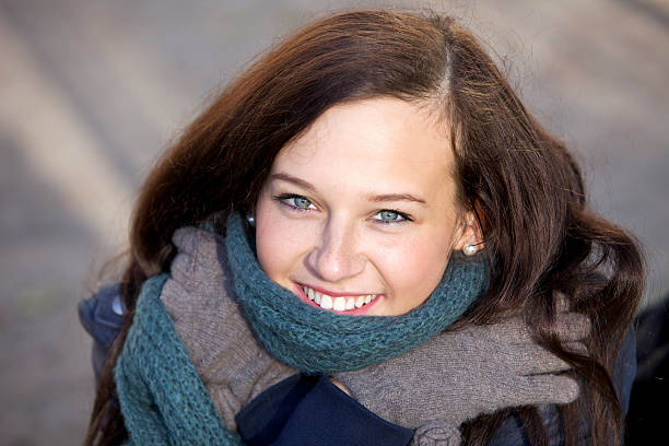 Attractive young woman in wool gloves and soft scarf smiling.