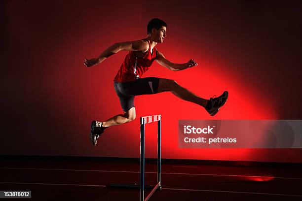 Foto de Atleta Correndo Obstáculos Isolado No Fundo Vermelho e mais fotos de stock de Obstáculo de Corrida