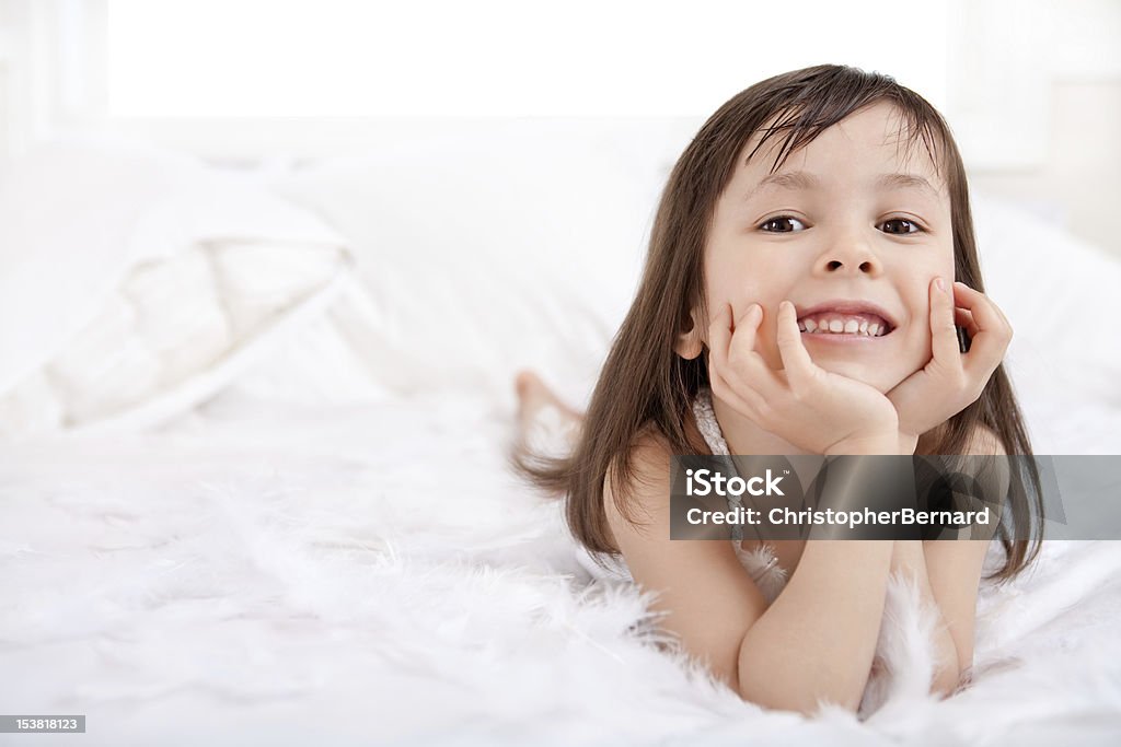 Sorridente menina brincando com penas no - Foto de stock de Edredom royalty-free