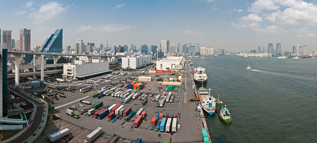 Panoramic view over the Port of Tokyo container dock harbor, the blue waters of Tokyo Bay and the downtown waterfront skyscrapers of Shiodome, Shimbashi, Ginza and Katchidoki, central Tokyo, Japan. ProPhoto RGB profile for maximum color fidelity and gamut.