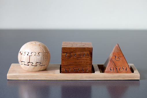 A wood sphere, cube and pyramid on gray background.