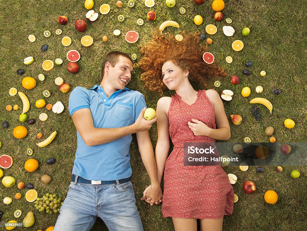 Couple with fruit Couple with fruit is lying on the grass Adult Stock Photo