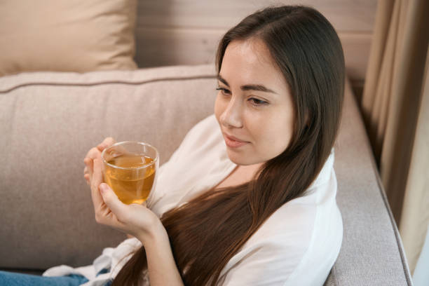 istock Smiling pretty young woman sitting on sofa 1538252755