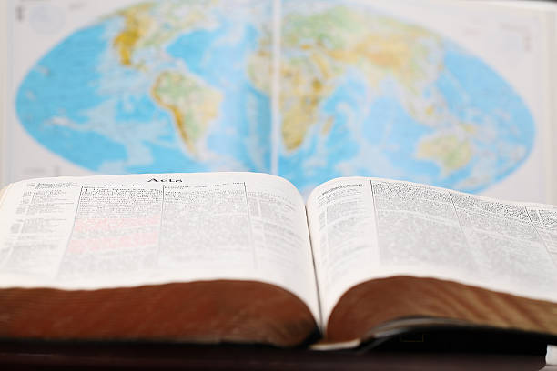 An open bible in front of a world map stock photo