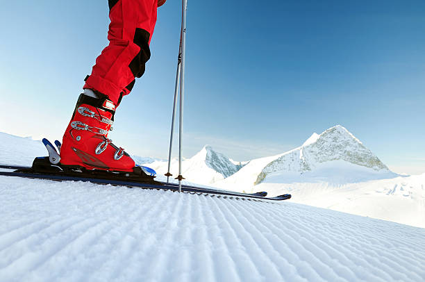 skier on an untouched ski track skier`s legs in ski equipment (boots, ski) on a freshly groomed ski track ready to go downhill, mountain landscape of Olperer summit at Hintertux red boot stock pictures, royalty-free photos & images