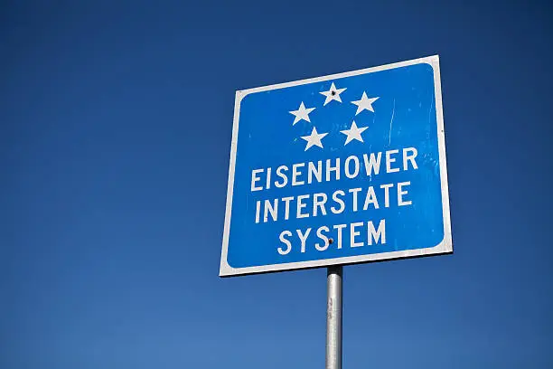 President Eisenhower is responsible for the creation of the interstate highway system criss-crossing the United States.  Eisenhower was a 5 Star General and that is represented in the sign.