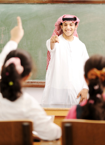 Arabic Muslim teacher in classroom with children.