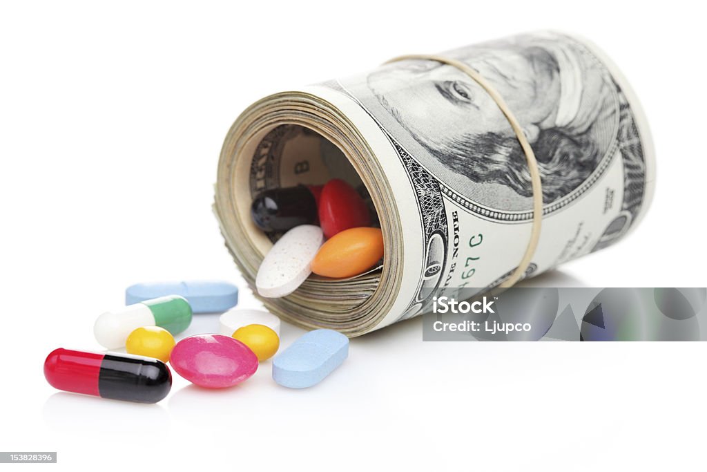 Money rolled up with pills flowing out Money rolled up with pills flowing out isolated on white background, high costs of expensive medication concept Capsule - Medicine Stock Photo