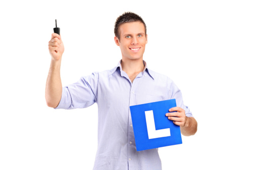 Happy man holding a car key and L plate isolated against white background