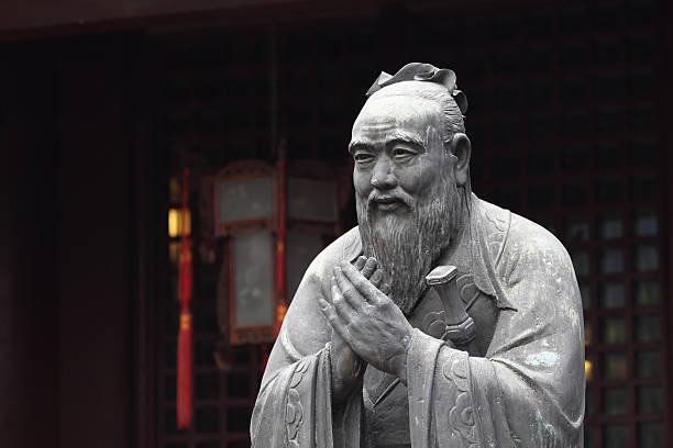 Freestanding, grey stone statue of Confucius outside temple stock photo
