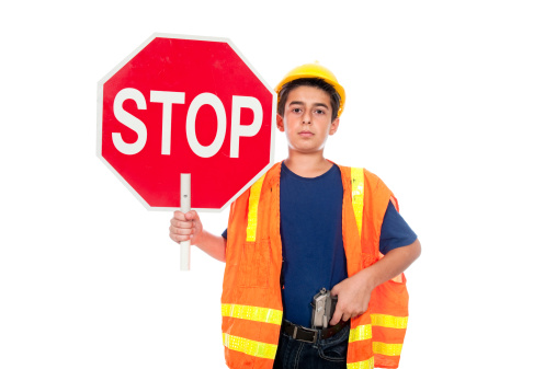 A boy directs traffic using a stop sign and a gun