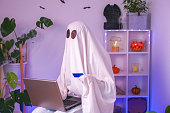ghost of Halloween uses a laptop to surf the Internet, to browse online stores, markets. A ghost makes an order from a computer for Halloween. Ghost pays for online purchase by credit card, bank card