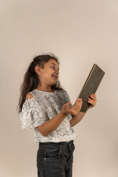 istock Child girl using a tablet in front of a white background. 1538338764