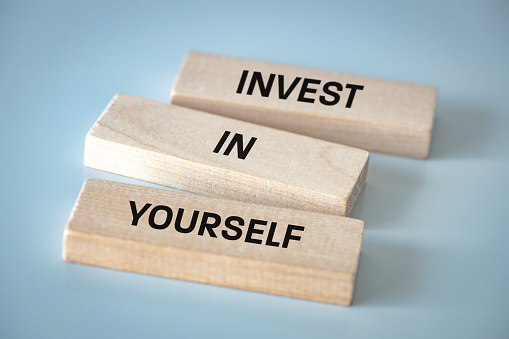 Invest in Yourself, wooden blocks form a slogan, Invest in Yourself, the concept of development and self-realization in life and business, Beautiful light blue background