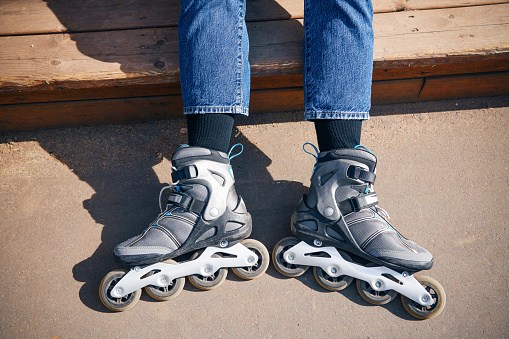 Young woman with roller skates in park. Rollerblading. Legs wearing roller skating shoe. Sport lifestyle.