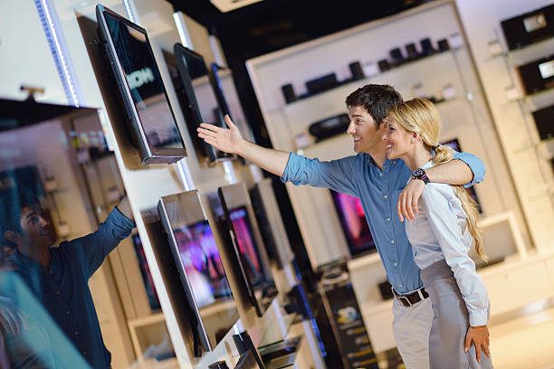 istock Smiling couple browsing TV choices in an electronics store 153855101