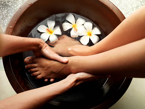 Relaxing pedicure Female feet in foot bath with flowers getting a pedicure foot spa treatment stock pictures, royalty-free photos & images