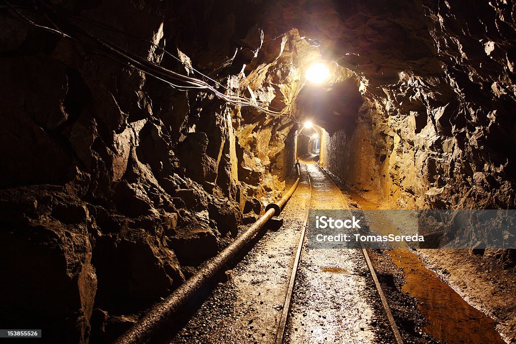 Ferrovia in esecuzione attraverso illuminato debolmente Pozzo di estrazione - Foto stock royalty-free di Miniera sotterranea