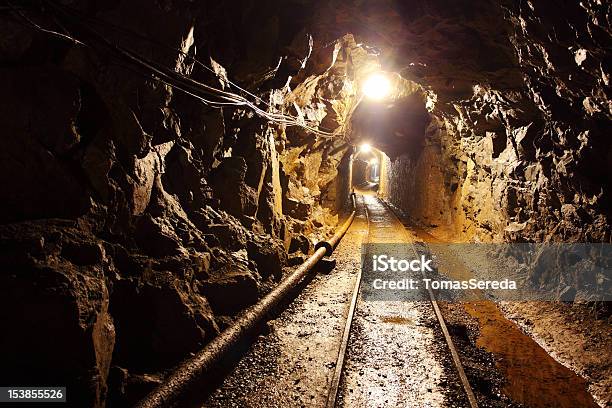 Ferrovia In Esecuzione Attraverso Illuminato Debolmente Pozzo Di Estrazione - Fotografie stock e altre immagini di Miniera sotterranea