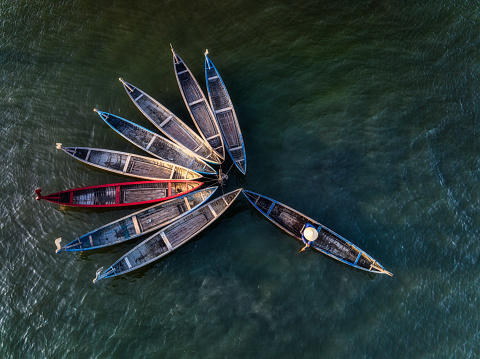 Drone view a woman is dragging and nailing wooden fishing boats, which made a flower shape on O Loan lagoon - Phu Yen province, central Vietnam