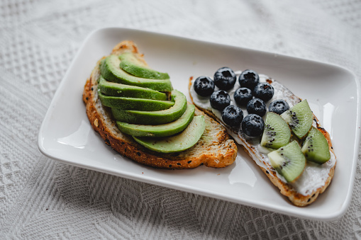 Avocado and blueberry kiwi toast on white background