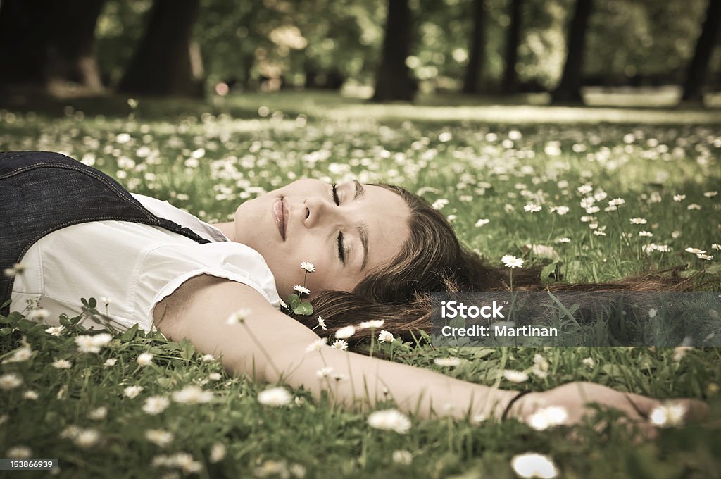 Młoda kobieta, leżąc na trawie z kwiatów - Zbiór zdjęć royalty-free (Beztroski)