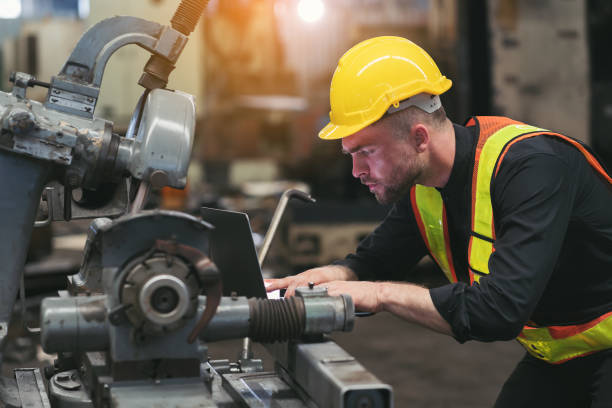 istock Male factory mechanic. Male engineer working or using computer laptop for checking machinery in industry factory and wearing safety uniform and helmet 1538675077