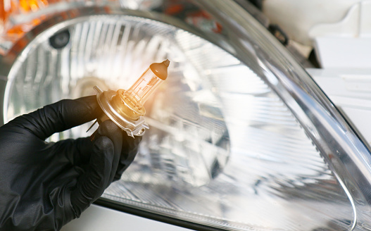 Car mechanic replace the damaged car light bulb and insert the new one