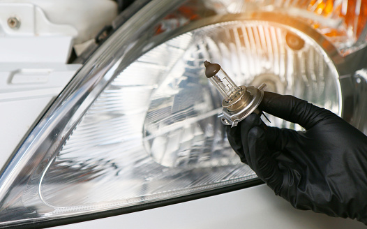 Car mechanic replace the damaged car light bulb and insert the new one. ,Under the concept of engine maintenance
