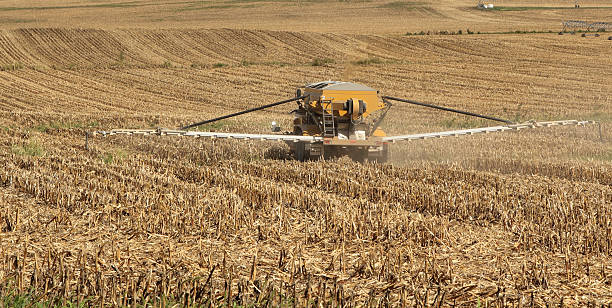 Spreading Agriculture Chemicals Vehicle spreading fertilizer on a farm field of corn stubble field stubble stock pictures, royalty-free photos & images