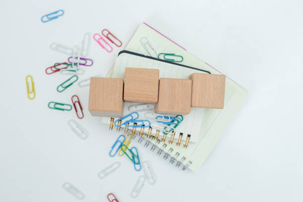 Wooden cube block empty on notebook with paper clip on white table. business object sign information. education and learning concept. copy space.