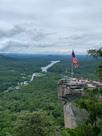 Chimney rock overlooking the mountains and river, American flag flying on edge of formation.