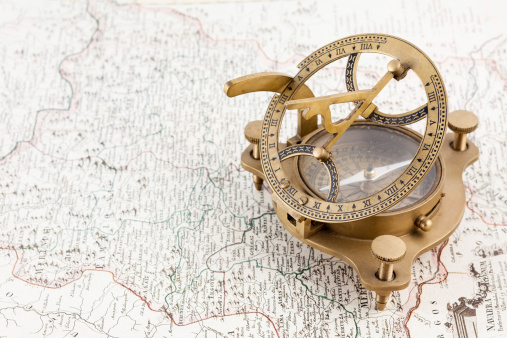 Old nautical sundial compass over an antique map