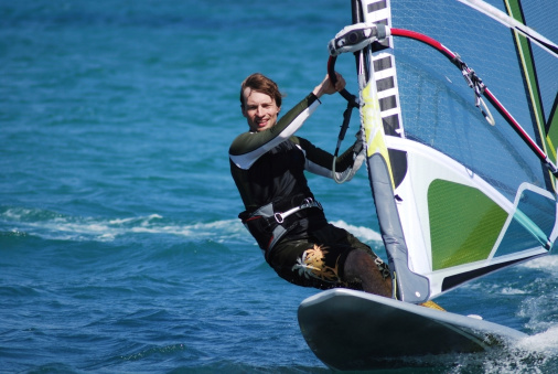 Young girl windsurfing in a blue sea in a summertime.