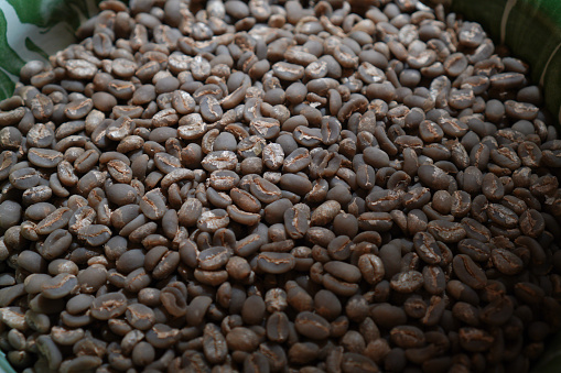 Cup of hot coffee with coffee beans on the brown background