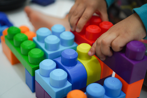little boy playing, using bright colorful constructor. He put blocks himself.