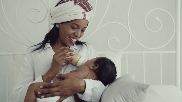 Cherishing Motherhood: African American Mom Nurturing Her Infant with a Milk Bottle | Joyful Bonding at Home